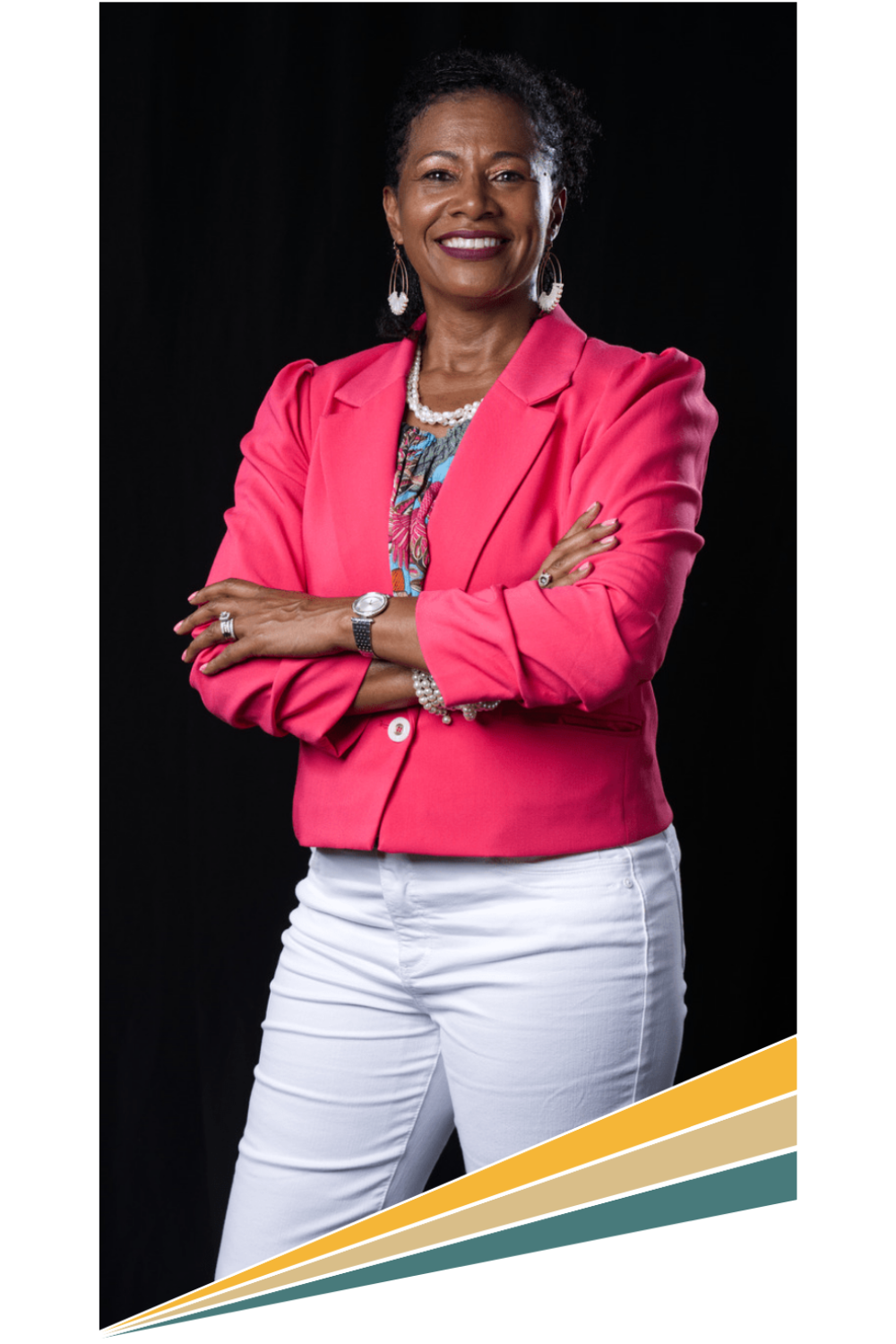 Casidy Sanders, with arms crossed, wearing a bright pink blazer over a floral blouse and white pants, set against a dark background.